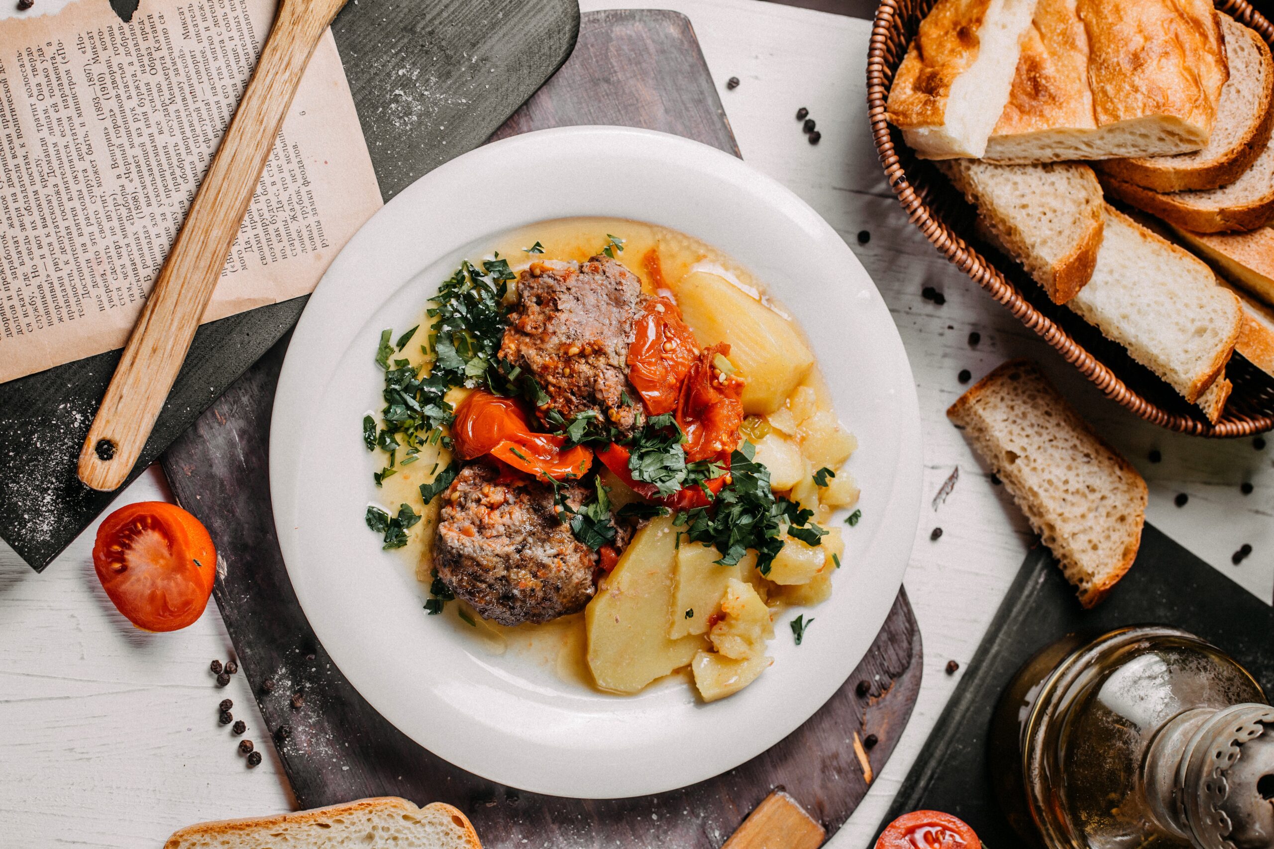 top view of stewed meat vegetables potatoes and herbs on a white plate